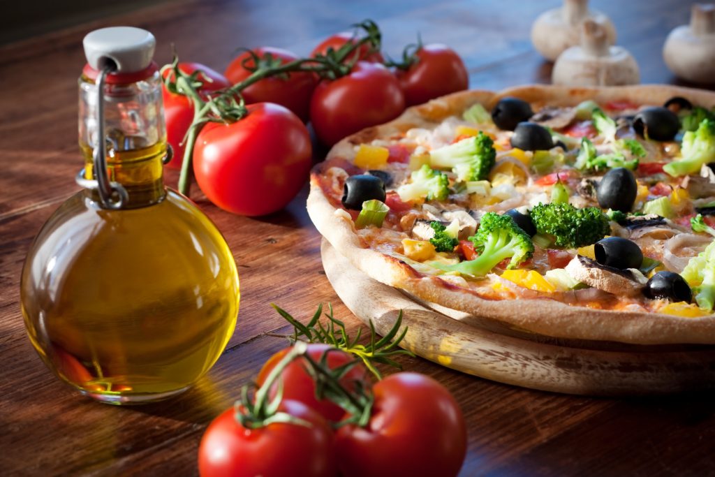 Plato de pizza con tomate, champiñones y aceite de oliva